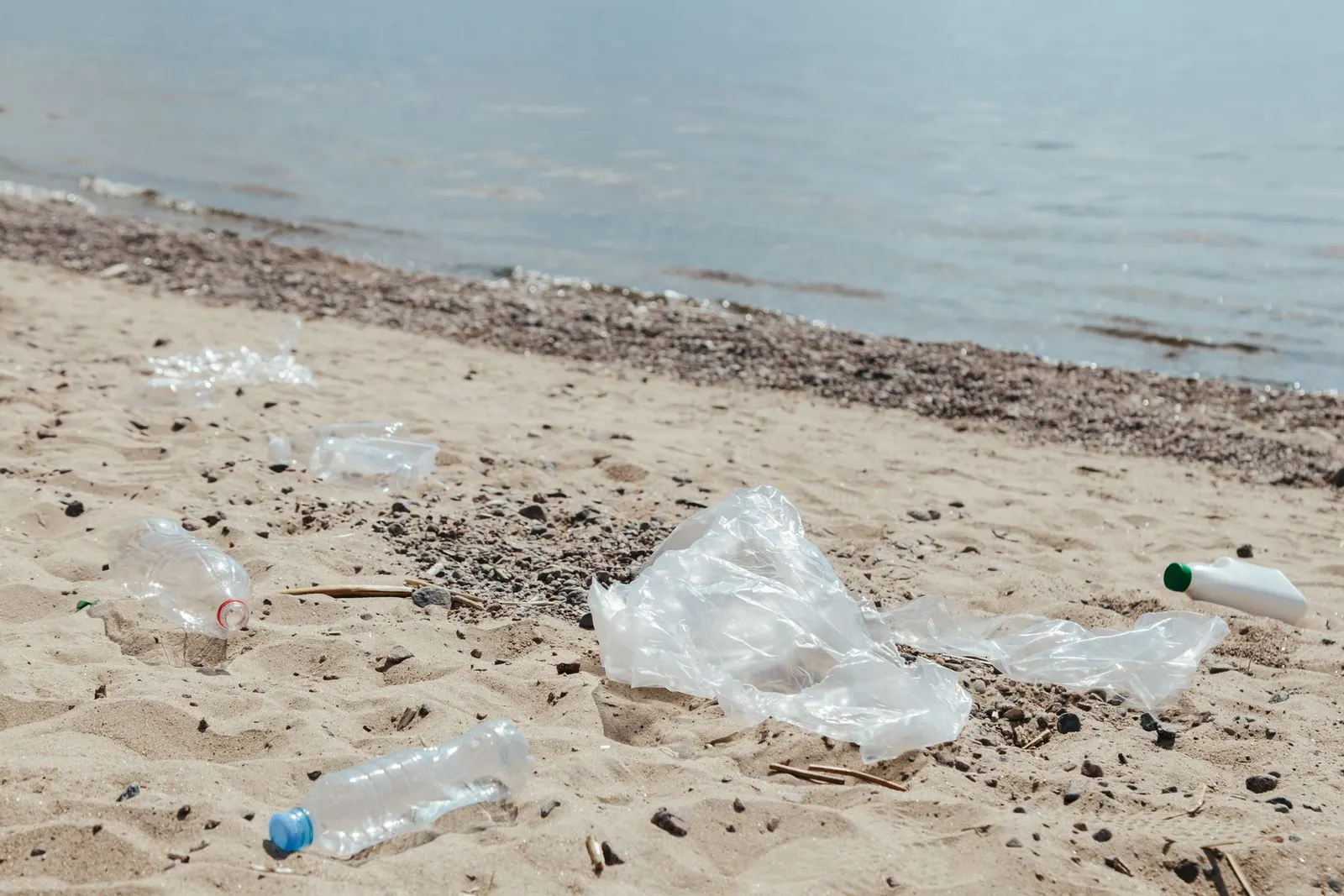 Plastic waste and litter scattered on a sandy beach, highlighting marine pollution